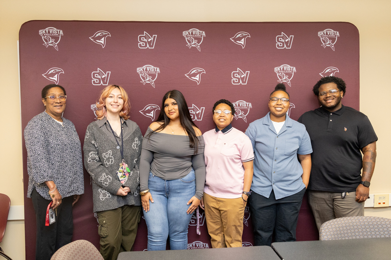 Six students pursuing the Aspiring Educator Pathway at Cherry Creek School District pose for a portrait in front of a maroon backdrop with Sky Vista Middle School logos. 