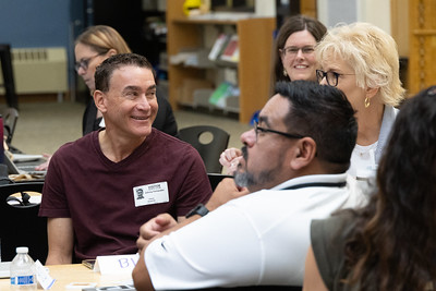 Group of educators seated at an event, talking, smiling, and listening